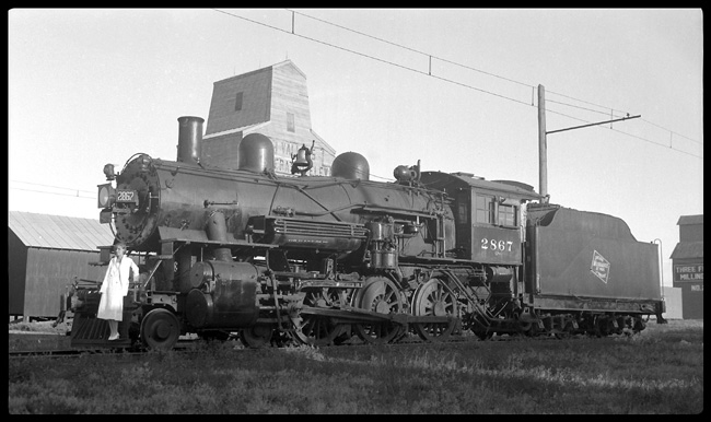 MILW 2867, 4-6-0 at Three Forks with probably Mrs. Nixon standing on pilot.