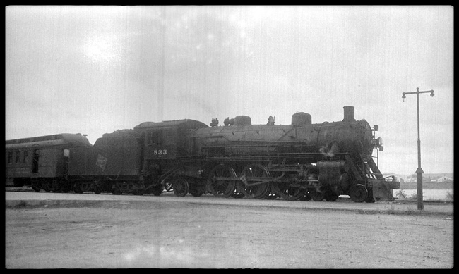 MILW 833. 4-6-2 Pacific type locomotive pulling a passenger type/baggage car, but location and actual date of photo not provided in index.