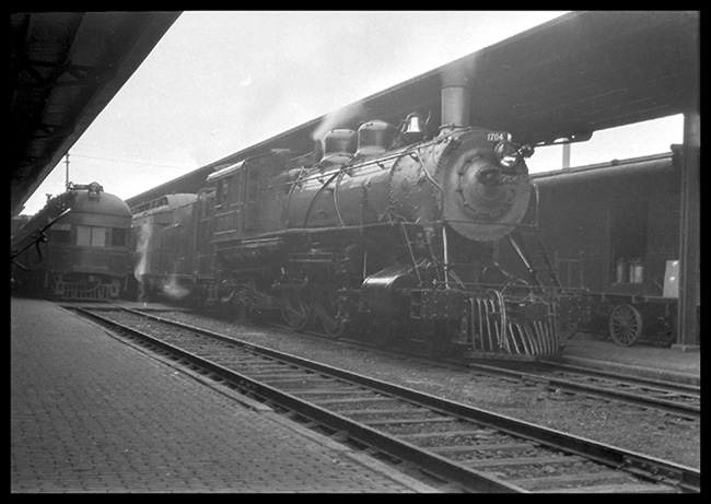 GN Passenger Eng No. 1704 at Duluth MN a GN class K-1  4-4-2  Baldwin 1906 alongside of Duluth Union Depot passenger shelter.  A gasoline railcar, possibly the Northern Pacific run from Staples, is on an adjacent track.