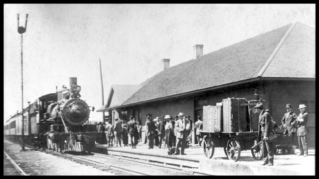 GN Passenger Eng 353 at Deer River, Minn. GN, 2-6-0.  This is an 1888 Rogers Mogul built for the Eastern Railway of Minnesota.  Baggage and two coaches,  Depot, Train order board,  Loaded baggage cart,  Large crowd of people