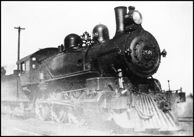 NP 208 Spokane WA 1903 copy negative from Melberg. NP208 is a class P-1, 4-6-0 passenger locomotive built in 1901 by Schenectady. The identity of the man standing by the pilot is unknown but from his appearance it may be inferred that he is a railroad official 