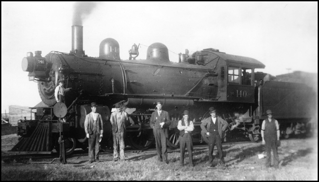 NP Mx train with NP 140, a 10 Wheeler 4-6-0 locomotive under steam with train ready to go. Several people posed for picture, including Fmn Holler, Condr Wermeers, Bkmn Garraghty, Ross and Fischer.
