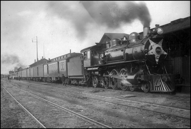 NP 281, Class Q, 4-6-2 at station with passenger train in Missoula. Crew servicing train.