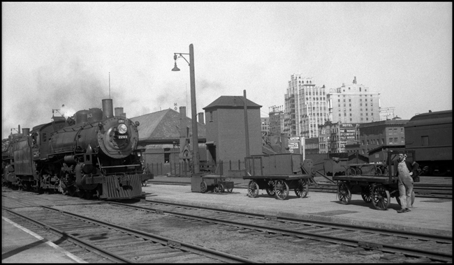 NP 2203, Pacific type, Class Q-4 in Spokane, WA, as it arrives double headed.  Baggage man waiting for train to stop.