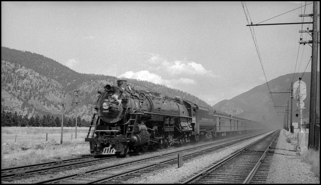 NP train No. 1 with NP 2665, Class A-3 and passenger cars near Bonner, MT and adjacent to Milwaukee track so that Milwaukee signal and electric catinary are visible. 