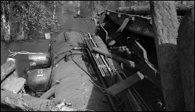 View of NP 1356, Class S-4, in water, with a log flat on top of locomotive, as X1356E with 28 log cars derailed into the Bitter Root River near bridge 23.2 caused by high water.  Killed Engr McFarland, Fmn Mc Gregor and Bkmn D'Orazi.