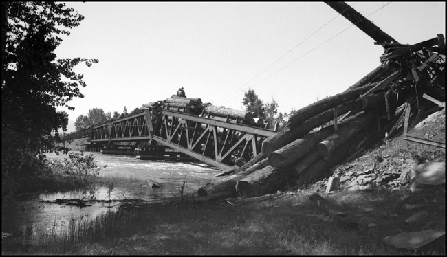 Longer view from the east of derailed log flats and bridge 23.2 were log train X1356E with 28 log cars derailed into the Bitter Root River caused by high water.  Killed Engr McFarland, Fmn Mc Gregor and Brkmn D'Orazi.