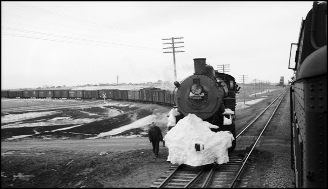 NP Train No. 800 with NP 1915, Class W-2 with the pilot covered with snow from drift busting, coming onto mainline which is being held by NP X6000E.  Photograph is taken from the trailing cab on NP 6000.