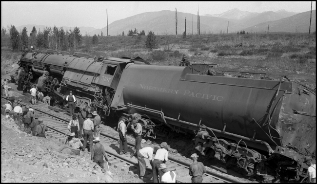 Many workers gathering around NP 5107, Class Z-6 as they prepare to rerail the locomotive after it derailed due to a broken frame.