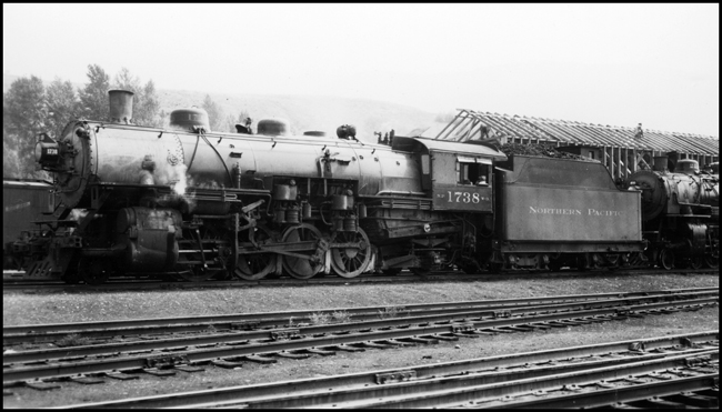 NP 1738, Class W-3 locomotive coupled to another engine in front a support building that is being constructed at Missoula.