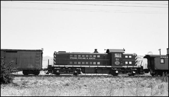 NP freight train at Missoula with SP&S 51, Alco road switcher in train ahead of caboose.  It is not indicated whether the SP&S 51 is operating as a helper or moving DIT, but it suspected the Alco is Dead in Train for movement to the SP&S at Portland.