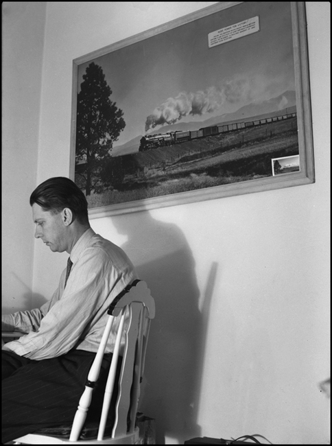 Ronald V. Nixon at his desk in his home at Missoula, Montana. One of his more famous photographs is displayed on the wall behind him.