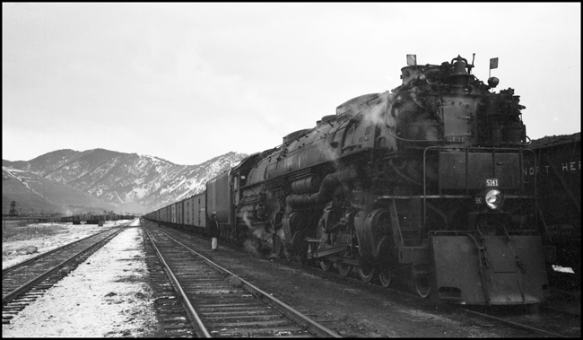 NP Extra 5141 West prepares to depart Missoula, Montana. The crew: Engineer Otto C. Behner; Fireman M. H. Slenes; Conductor Byron W. Jenison; and Brakemen T. L. Sparks and L. N. Olsen. Engineer Behner is the oldest among these men, having been hired as a fireman in June 1908 and promoted to engineer in October 1917. The youngest is Olsen, hired in February 1937. Ron Nixon rode in the cab with the engine crew to Paradise so as to obtain publicity photos of a string of new refrigerator cars that were in the train. Ron had permission to stop the train anywhere he wished for this purpose. The series of photos of this train between Missoula and Paradise were the results of his effort.