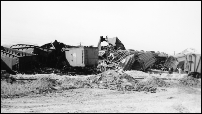 Damage to cars after Extra 5121 West rear-ended the main line local, Extra 1816 West, at Drummond, MT. This accident resulted indirectly from the events surrounding the derailment of wrecker 47 east of Missoula (see RVN09581-09595). Missoula engineer Charles F. Reinke and his fireman had been on a layover in Helena when they were called to take Helena wrecker no. 37 to Missoula to help re-rail wrecker 47. In the meantime, officials decided to use a small wrecker from the Missoula car shop to assist wrecker 27 for that job, so Reinke and his fireman were stopped at Garrison and sent back to Helena. Then, after returning to Helena, they were called short of their legal rest period to handle Extra 5121 West. According to railroad officials, as Reinke approached Drummond he and his fireman had probably fallen asleep and missed block signals protecting the rear of Extra 1816 West. Extra 1816 West's conductor looked out the back of his caboose just in time to see the high speed approach of Extra 5121 West, so he ran into the nearby field. His brakemen were already on the ground giving signals for switching moves they were making at Drummond. The big Z-7 4-6-6-4 type locomotive plowed into the local's wooden caboose at high speed. There were only minor injuries to the crews involved. Conductor Emil Berglin was in charge of Extra 5121 West. Engineer Elmer Walkup and Conductor Malcom McCauley were handling the local.