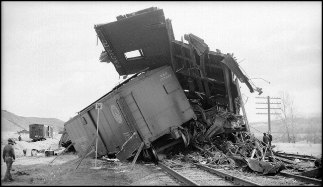 Extra 5121 West rear-ended the main line local, Extra 1816 West, at Drummon, MT. This accident resulted indirectly from the events surrounding the derailment of wrecker 47 east of Missoula (see RVN09581-09595). Missoula engineer Charles F. Reinke and his fireman had been on a layover in Helena when they were called to take Helena wrecker no. 37 to Missoula to help re-rail wrecker 47. In the meantime, officials decided to use a small wrecker from the Missoula car shop to assist wrecker 27 for that job, so Reinke and his fireman were stopped at Garrison and sent back to Helena. Then, after returning to Helena, they were called short of their legal rest period to handle Extra 5121 West. According to railroad officials, as Reinke approached Drummond he and his fireman had probably fallen asleep and missed block signals protecting the rear of Extra 1816 West. Extra 1816 West's conductor looked out the back of his caboose just in time to see the high speed approach of Extra 5121 West, so he ran into the nearby field. His brakemen were already on the ground giving signals for switching moves they were making at Drummond. The big Z-7 4-6-6-4 type locomotive plowed into the local's wooden caboose at high speed. There were only minor injuries to the crews involved. Conductor Emil Berglin was in charge of Extra 5121 West. Engineer Elmer Walkup and Conductor Malcom McCauley were handling the local.