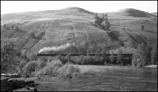 An extra west rolls past the southern face of Mount Jumbo, east of Missoula, on a well-maintained double track line built in 1908. The train will soon be entering Missoula yard.