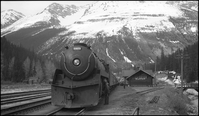 CPR 5923, 2-10-4 with CPR Train No. 3 behind, at Glacier, BC depot.  Engineman inspecting running gear.