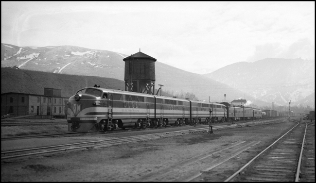NP Train No. 603 powered by Electro Motive 103, experimental diesel electric locomotive arrives Missoula on test run from Northtown to Auburn.  NP Dynamometer Car behind locomotive with Pullman and business car behind, ahead of freight train.