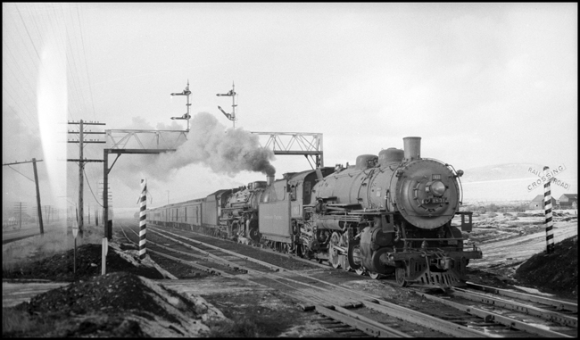 The road engine seems to be doing all the work.  A double header brings the North Coast Limited east on a moist spring day.  Snow is melting and the Montana winds are favorable for a while.  The lead engine will be one of the last NP steamers to make a mainline freight run, in 1957.