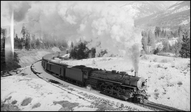 A hard working Northern lweads the North Coast Limited around a curve at Evaro MT.  Out of sight, but valuable indeed, an old Mikado is giving a boost from the rear.