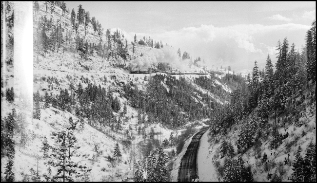 The tracks are far above the highway, and a close study will spot the North Coast Limited west, doubleheaded as usual, with a W-3 and an A.