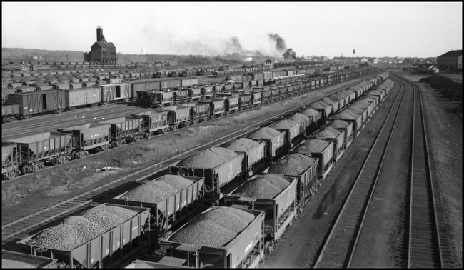 Duluth Minnesota and Iron Range RR Yard in Proctor, MN with lots of loaded ore cars full of iron ore. Coal dock in background.