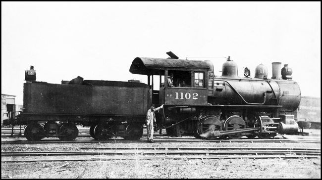 NP 1102, Class L-9 locomotive with crew member on the ground posing for camera.