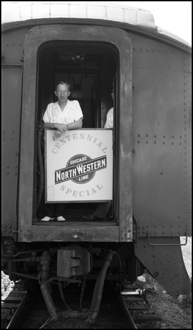 Harold Ashcroft in rear vestibule of CNW Centennial Special, showing tail sign, St. Paul.