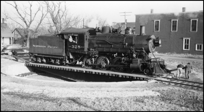 NP 328, Class S-10 being turned on a strong arm turntable at Grantsburg, WI.  Three crew members are manning the turntable.