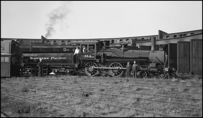 NP 684, a 4-4-0 American Std Class C-1 and former NP 342, at Spokane.  Maynard G. Nixon and F. G. Radford are in the cab and J. J. Brendal and T. L. Goos are by the drivers.