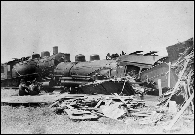 Photograph of a head-on collision between NP 1610 and NP 1619, both Class W, Mikado locomotives. Workers setting on the ground looking at the wreck.