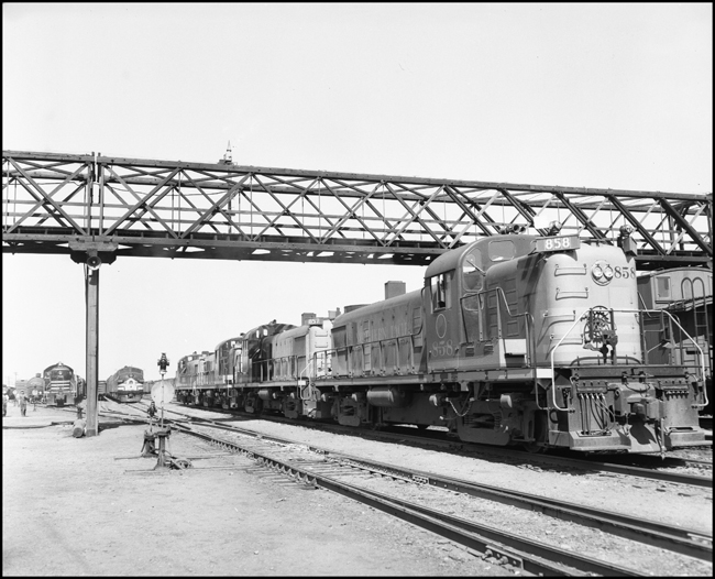 Alco locomotives NP 858, NP 857, NP 859 and NP 860 moving in consist in Missoula freight yard.  Other diesel electrics deeper in yard.
