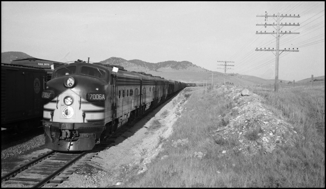 NP 7006, an EMD F-9A is west bound, flags flying with an extra freight at Birds Eye, MT.