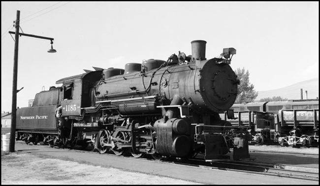 NP 1185, Class G-2 at Missoula with workman climbing into locomotive cab.