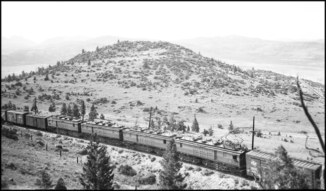 MILW E29 electric locomotive helper in a freight train near Cedric, MT.