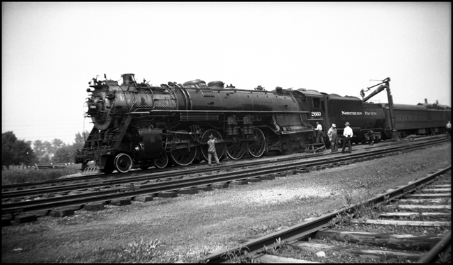 NP Class A-3 4-8-4 Northern no. 2663 takes water and has rods greased at unknown station, heading passenger train.
