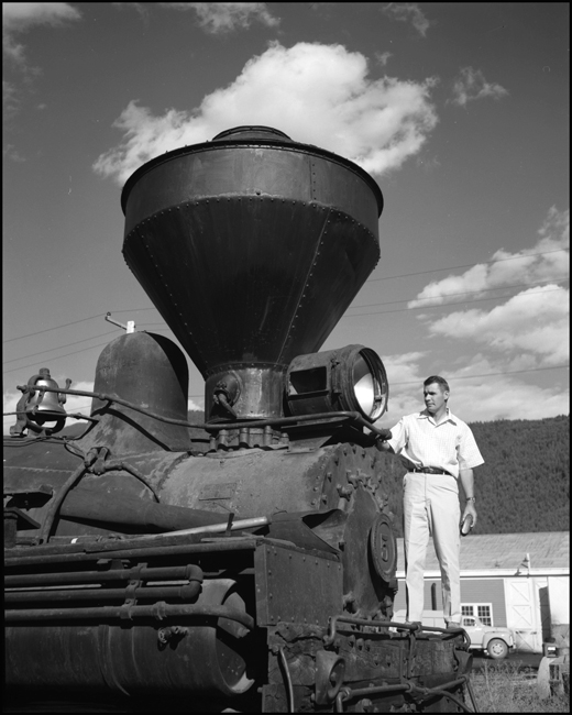 Putting things in perspective, a man overshadows a locomotive but is dwarfed by its smokestack.  Jack Hoover rides the pilot of a Shay
