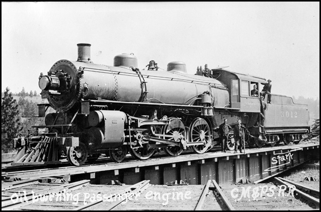 A top of the line passenger engine for the new Pacific Coast extension of the Milwaukee Road, this oil-burning Pacific poses with crew and friends on a turntable somewhere out west.
