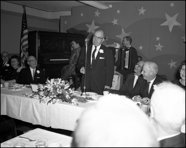 A gathering of railroad executives share speeches and dinner.  It is the start of a hard time for the industry in general, but times are prosperous on the Northern Pacific
