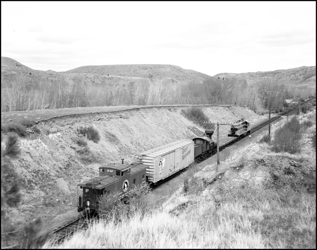 Great Northern had the cheeriest cabooses around, fire engine red and decorated with railroad mascot Rocky Mountain Bill.  A prime example is at the rear of this special train, bringing a Shay to a new home in Great Falls