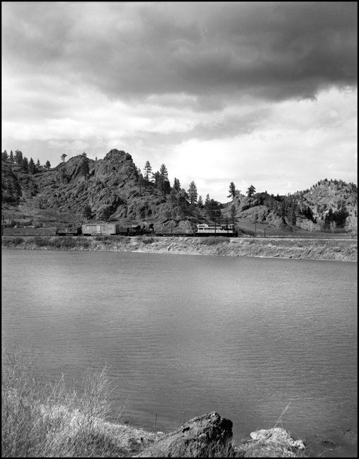 Leaving the canyon and pulling slowly north, a special train is bringing a log-train locomotive north from a repair shop at Missoula to a meseum at Great Falls