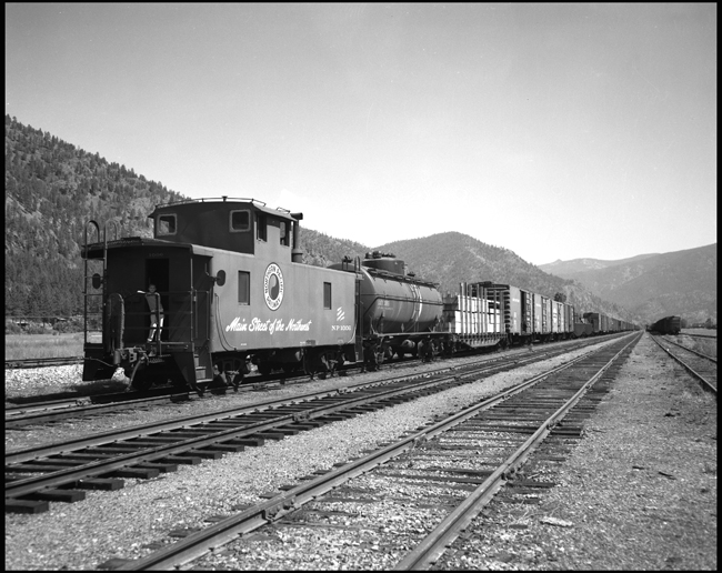 LDN, one of the Nixon Children or relatives standing on NP caboose 1006 behind the Fruit XE at Paradise, MT.