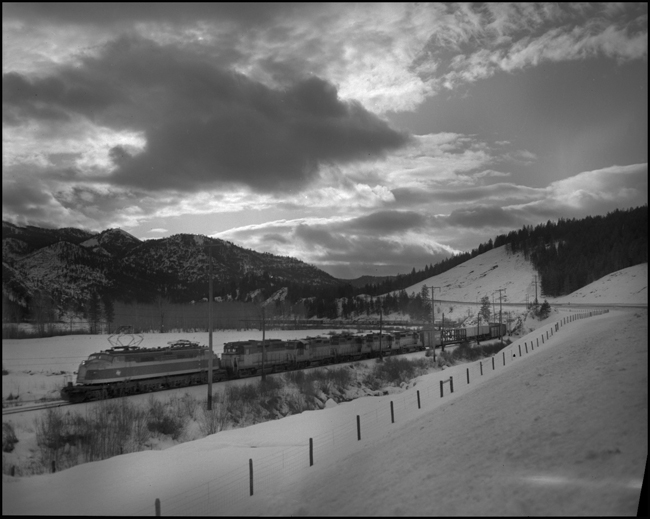 MILW No. 264 freight train west of Huson, MT, pulled by a mixed consist of electric and diesel power.