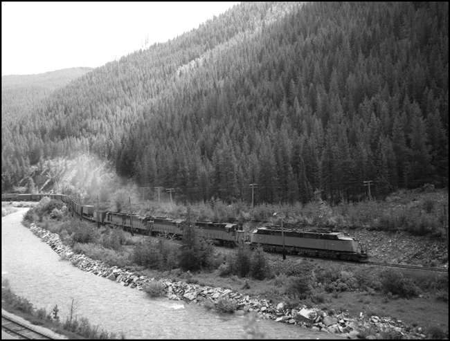 Westbound MILW freight no. 261 with Little Joe motor E-73 and 4 GP-40 diesels roars upgrade near Saltese, MT.