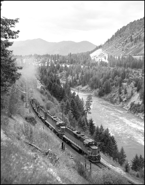 MILW GP-40 diesels and dead Little Joe motor detour an eastbound freight over the NP at Fish Creek, MT.
