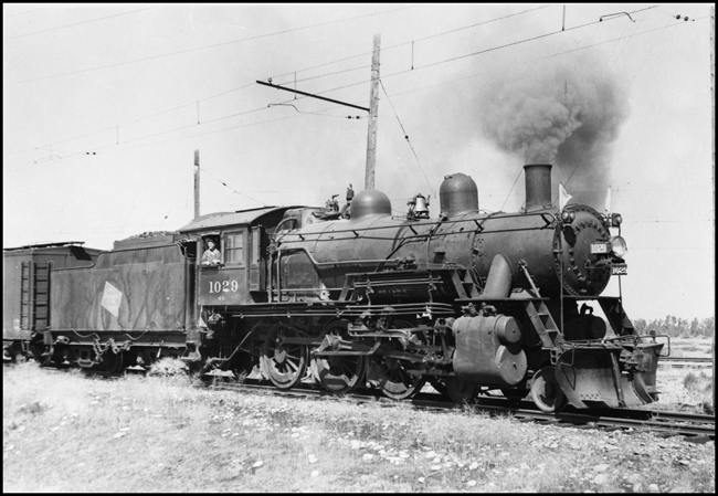 The engineer is in the cab of plow-piloted MILW 4-6-0 no. 1029 as it heads a local freight at Three Forks, MT.