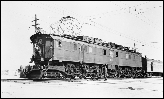 The fireman watches from the cab as the engineer inspects the running gear of his giant MILW Westinghouse Class EP-3 electric locomotive no. E-15 on the westbound Olympian at Three Forks, MT.