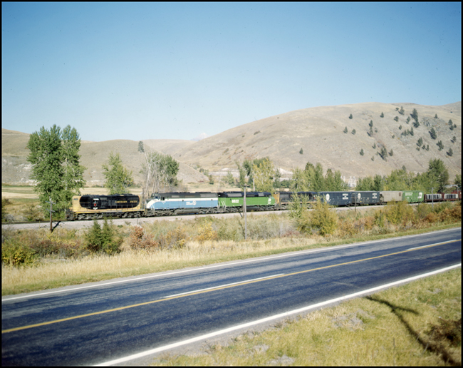 Color photo of BN extra 1747W west of Ravalli, MT.  First and fourth unit in consist are in NP paint.  Middle two units are F45s, first in GN sky blue paint and second one in BN green paint.
