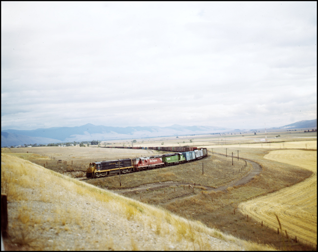 Color photo of BN extra 5609W near DeSmet, MT.  The lead unit is a U25C in NP paint, the second unit is a SD24 in CBQ paint, and the third unit is a SD24 in BN green.