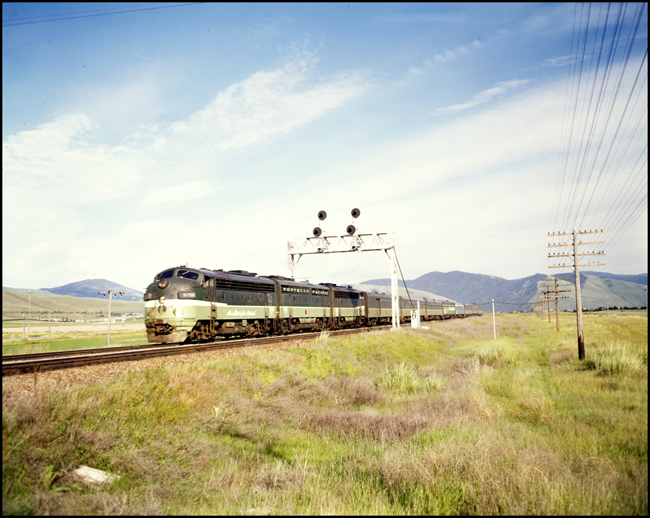 Color picture of Amtrak passenger train west bound with a set of BN F units A-B-A in NP paint west of Missoula, MT.